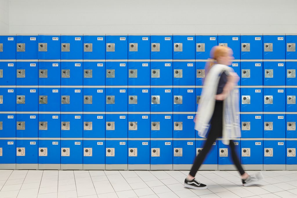 Girl walking past bank of lockers