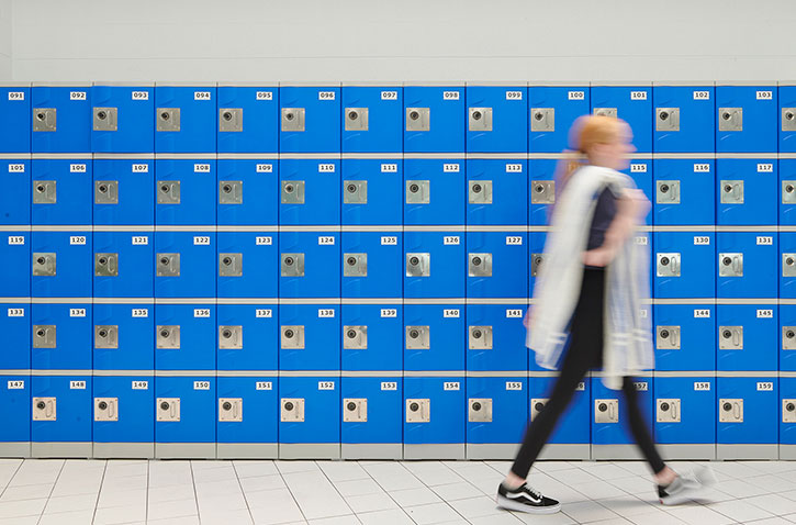 girl walking in front of blue lockers